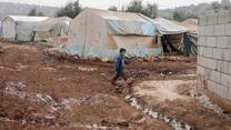 A boy walking through muddy barracks 